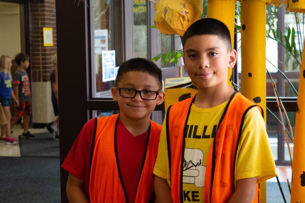 Two students posing wearing orange vests